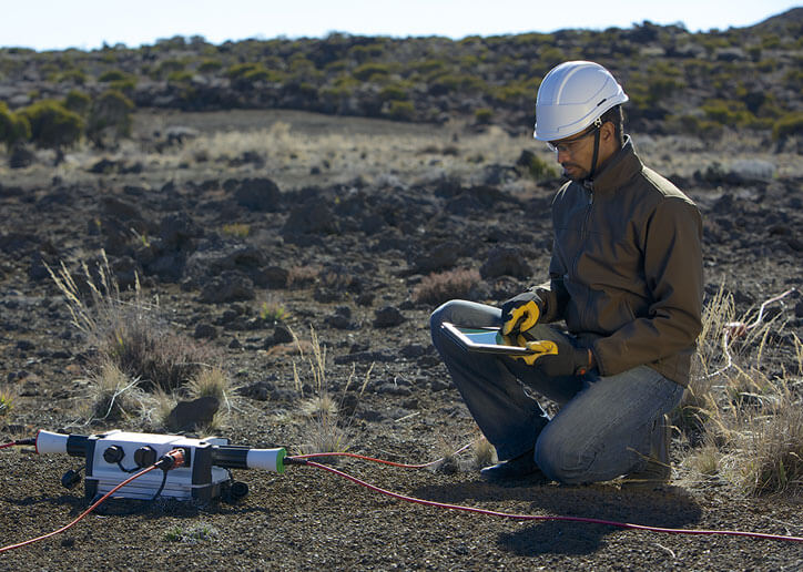 A geoscientist looking at readouts on his tablet